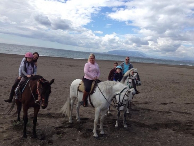 familia paseando a caballo por la playa